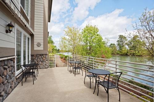 a balcony with tables and chairs next to a river at Holiday Inn Express Corvallis-On the River by IHG in Corvallis