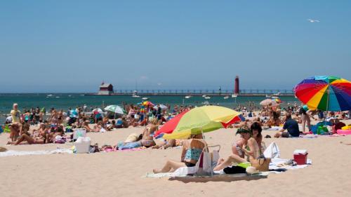 a crowd of people on a beach with umbrellas at Holiday Inn Grand Haven-Spring Lake by IHG in Spring Lake
