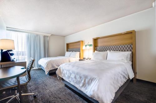 a hotel room with two beds and a desk and a table at Holiday Inn Grand Haven-Spring Lake by IHG in Spring Lake
