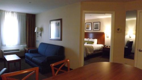 a hotel room with a bed and a blue couch and a table at Candlewood Suites Fredericksburg by IHG in Fredericksburg