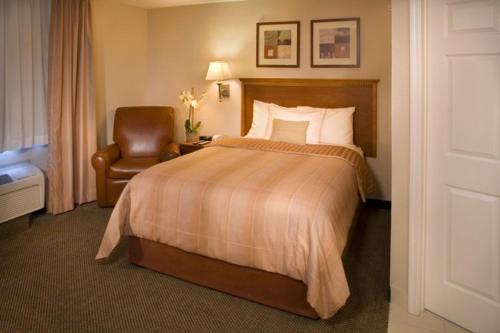 a hotel room with a bed and a chair at Candlewood Suites Fredericksburg, an IHG Hotel in Fredericksburg