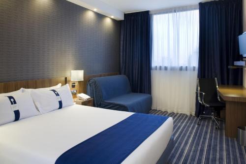 a hotel room with a bed and a chair and a desk at Holiday Inn Express Campo de Gibraltar-Barrios by IHG in Los Barrios