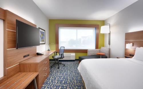 a hotel room with a bed and a flat screen tv at Holiday Inn Express & Suites - Gainesville I-75 by IHG in Gainesville
