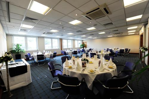 a conference room with tables and chairs with white table cloth at Holiday Inn Edinburgh Zoo, an IHG Hotel in Edinburgh
