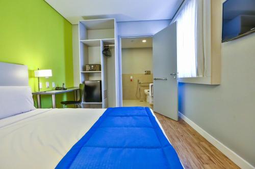 a bedroom with a large bed and a desk at Go Inn Santo André in Santo André