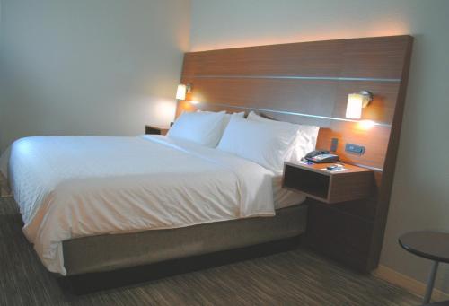 a hotel room with a large bed with a wooden headboard at Holiday Inn Express & Suites - Columbia City by IHG in Columbia City