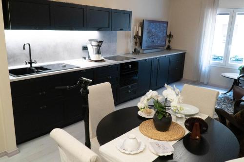 a kitchen with black cabinets and a table with a sink at Beauty Case intimate, quiet and central apartment in Bologna