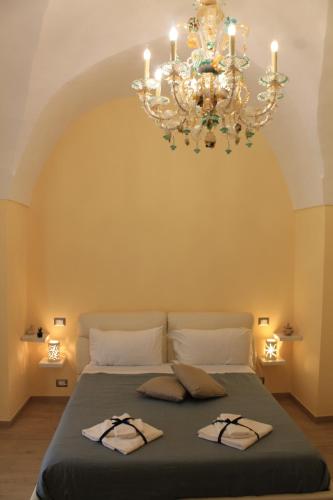 una camera da letto con un grande letto e un lampadario a braccio di Arco Suite a Lecce