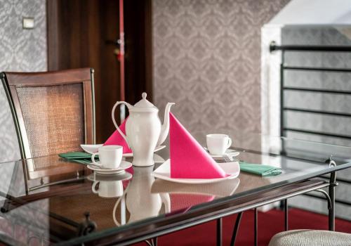 a glass table with pink and white plates and cups at Villa Zdrojowa in Otmuchów