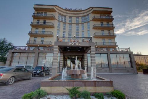 a hotel with a fountain in front of a building at Karagat Hotel in Karakol