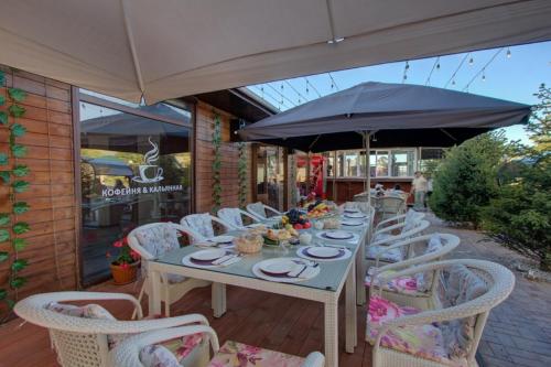a table with chairs and an umbrella on a patio at Karagat Hotel in Karakol