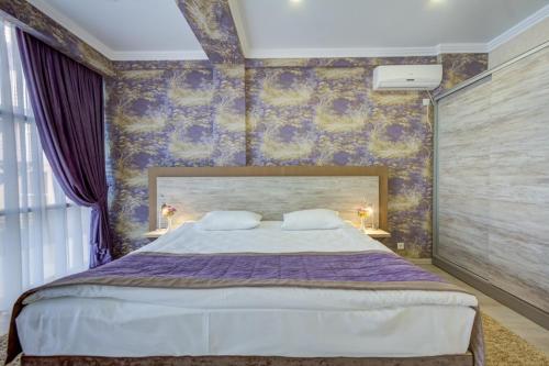a bedroom with a large bed with purple walls at Karagat Hotel in Karakol