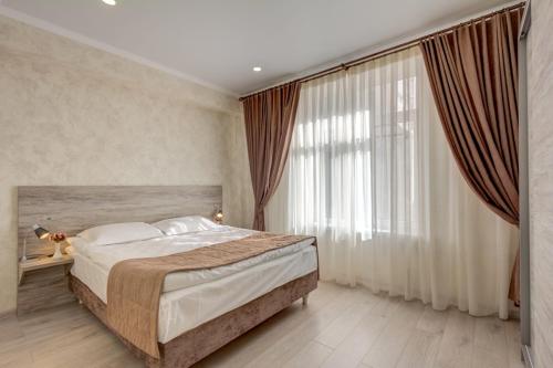 a bedroom with a large bed and a large window at Karagat Hotel in Karakol