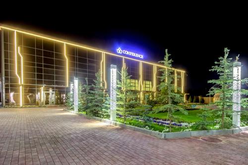 a lit up building with trees in front of it at Karagat Hotel in Karakol