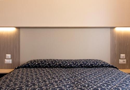 a bedroom with a bed with a blue comforter at Hotel Mediterraneo in Civitavecchia
