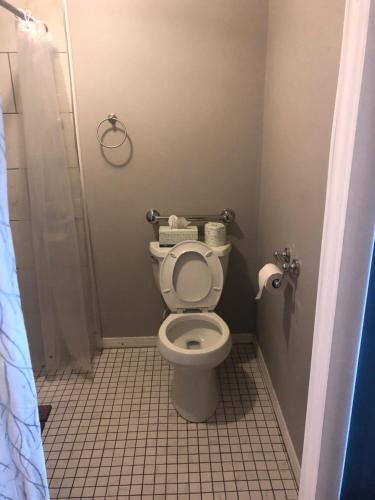 a bathroom with a toilet and a tiled floor at Malaga Inn in Mobile