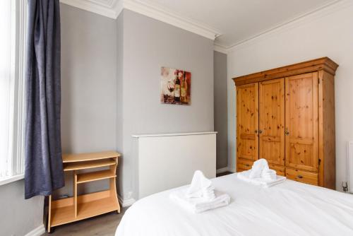 ニューポートにあるHandpost Lodgeの白いベッドと木製キャビネット付きのベッドルーム1室が備わります。