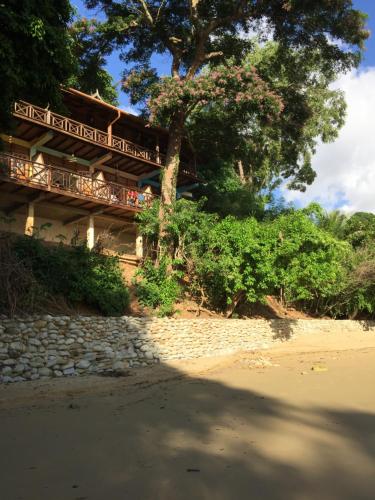 a building on the beach next to a tree at Alibaba‘s Seabreeze in Castara