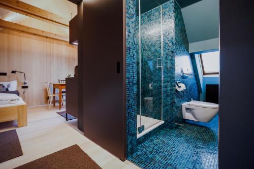 uma casa de banho com um WC e um chuveiro com azulejos azuis em AUGUST Dachgeschosswohnung im jüdischen Viertel em Hohenems