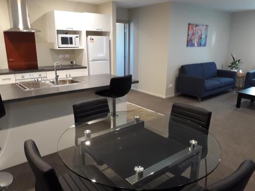 a living room with a glass table and a kitchen at South City Accommodation Unit 2 in Invercargill