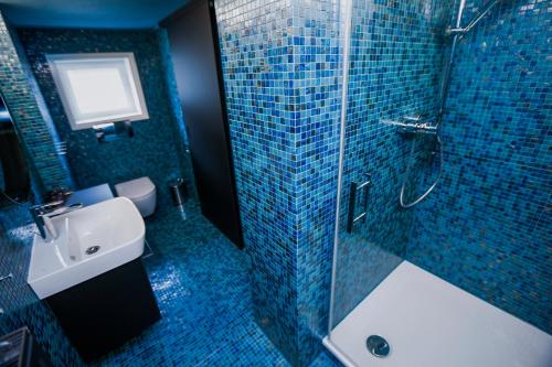 a blue tiled bathroom with a sink and a shower at MINA Stadtwohnung im Jüdischen Viertel in Hohenems