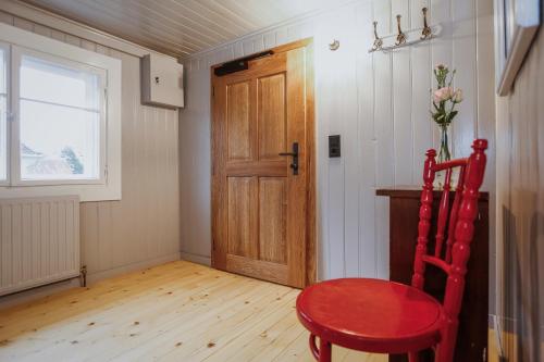 a room with a red chair and a wooden door at MINA Stadtwohnung im Jüdischen Viertel in Hohenems