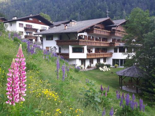 a building on a hill with a field of flowers at Hotel St. Pankraz in San Pancrazio dʼUltimo