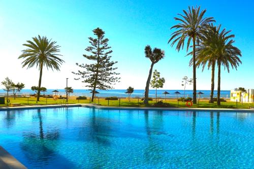 a swimming pool with palm trees and the ocean at Magical Sea View Studios II in Torremolinos