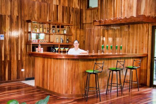 a woman sitting at a bar in a wooden room at Jaguarundi Jungle Lodge - Monteverde in Monteverde Costa Rica