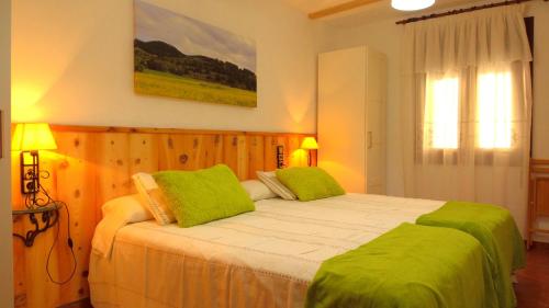 1 dormitorio con 1 cama grande con almohadas verdes en Apartamento Carrascales o Pinar Ciego, en Mosqueruela