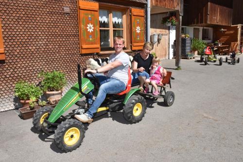 a man and a woman riding on a toy tractor at Kinderbauernhof in Schoppernau