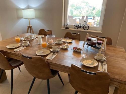 un tavolo in legno con sedie, piatti e bicchieri di Hotel B&B MAMA MIA a Obrovac (Obrovazzo)