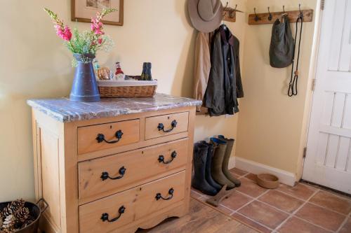 een dressoir met een blauwe vaas met bloemen erop bij Thatch Cottage - luxury Norfolk Hideaway in Norwich