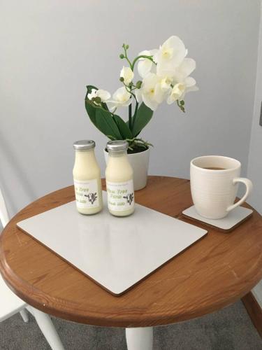 a table with two bottles and a cup and flowers at The Loft in Congleton