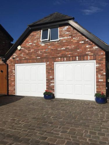 a brick house with two white garage doors at The Loft in Congleton