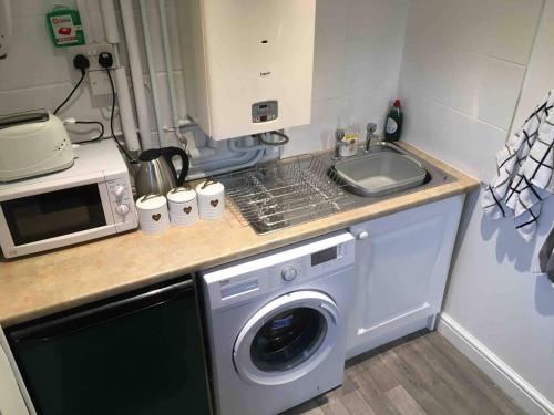 a kitchen with a washing machine and a microwave at The Loft in Congleton