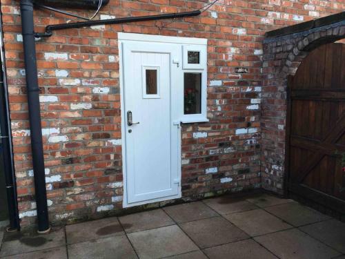 a brick wall with a white door on it at The Loft in Congleton