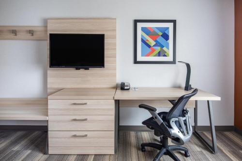 a desk with a television and a chair in a room at Holiday Inn Express Ontario by IHG in Creekside