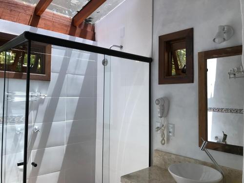 a bathroom with a glass shower and a sink at Regina Guest House in Praia do Rosa