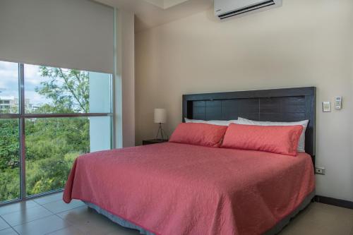 a bedroom with a bed with a red bedspread and a window at San Pedro Hotel, 5ta Avenida in Playa del Carmen