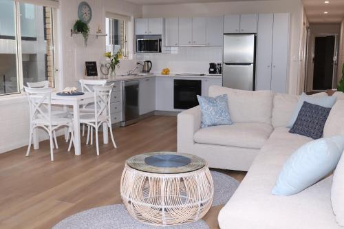 a living room with a white couch and a kitchen at Waterviews on Marine Pde 3/32 in The Entrance