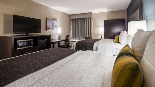 a hotel room with two beds and a flat screen tv at Best Western Plus Indianapolis NW Hotel in Indianapolis