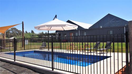a black fence with an umbrella and a swimming pool at Dubbo Rhino Lodge in Dubbo