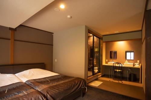 a bedroom with a large bed and a bathroom at Kusatsu Onsen Eidaya in Kusatsu