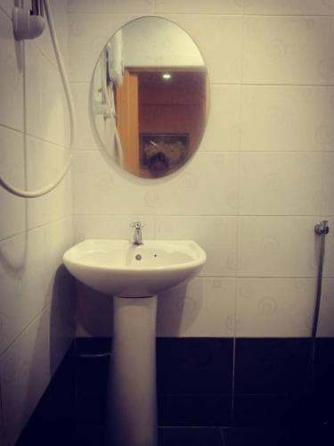 a bathroom with a white sink and a mirror at Weng Kong Homestay in Slim River