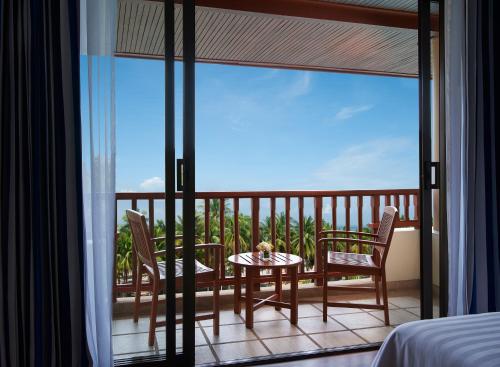 een kamer met een balkon met een tafel en stoelen bij The Tide Resort in Bangsaen