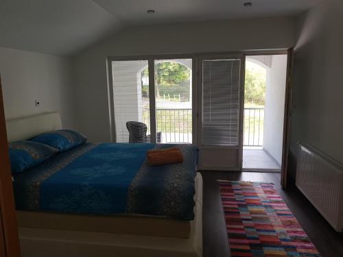 a bedroom with a bed with a blue comforter and a window at Vinac guest house in Jajce