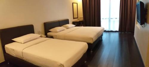 a hotel room with two beds and a window at Manja Hotel in Kota Kinabalu