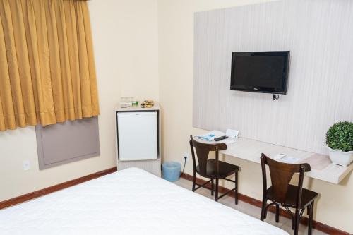 een kamer met een bed, een bureau en een televisie bij Palácio Do Rio Hotel in Teresina