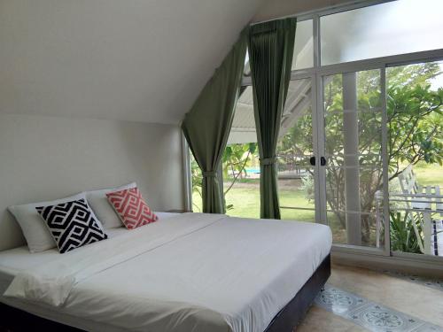 a bed in a room with a large window at Ban Bang Home Resort in Haad Chao Samran
